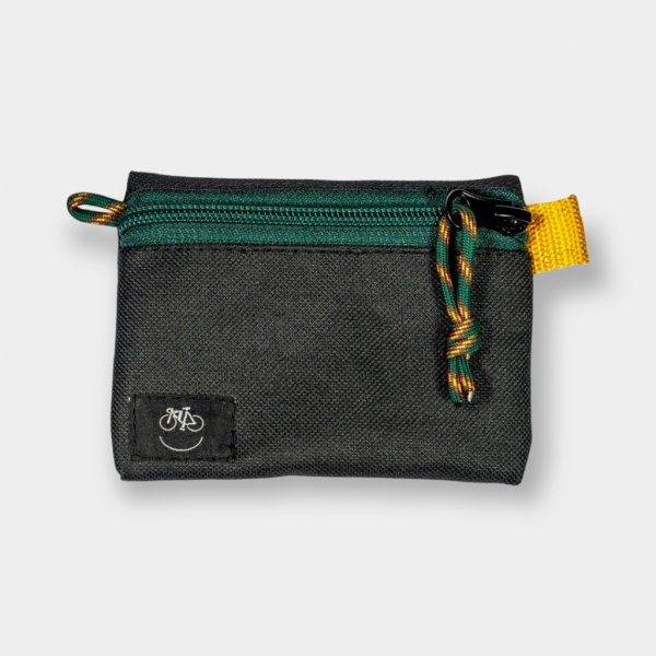 Bolsa accesorios small en color negra con el tirador de la cremallera verde y naranja de Chela Clo